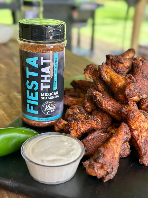 Fiesta That seasoning bottle with fried wings and a side of sauce on a wooden surface.