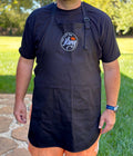 Person wearing a black apron with a logo outdoors on a grassy area