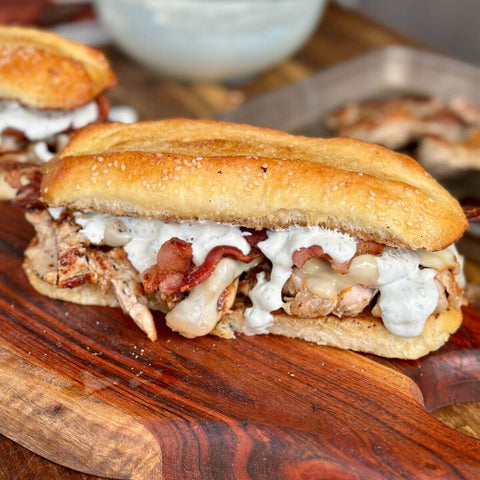 Sandwich with bacon and cheese on a wooden cutting board