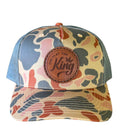 Camouflage-patterned cap with a brown leather patch on a white background
