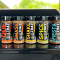Five bottles of seasoning on a grill with a blurred outdoor background