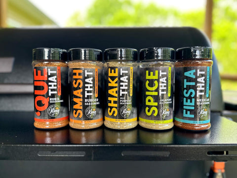 Five bottles of seasoning on a grill with a blurred outdoor background